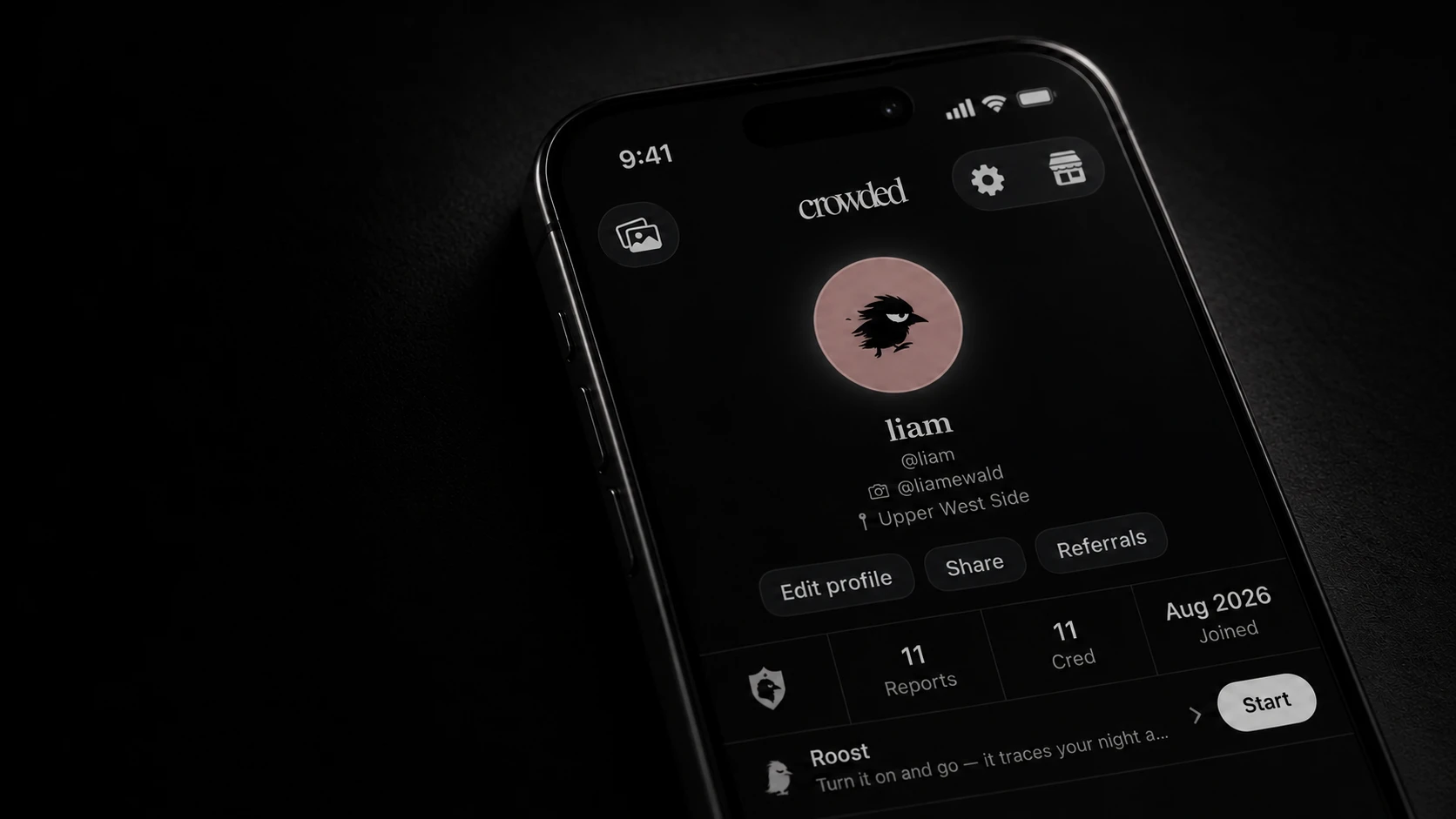 A black iPhone lying tilted in the dark, showing the top of a Crowded profile - the avatar, the name, Reports, Cred and the Roost row with its Start button.